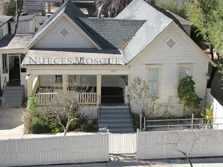 A small house-form mosque with a porch, front gate, and Nueces Mosque lettering.