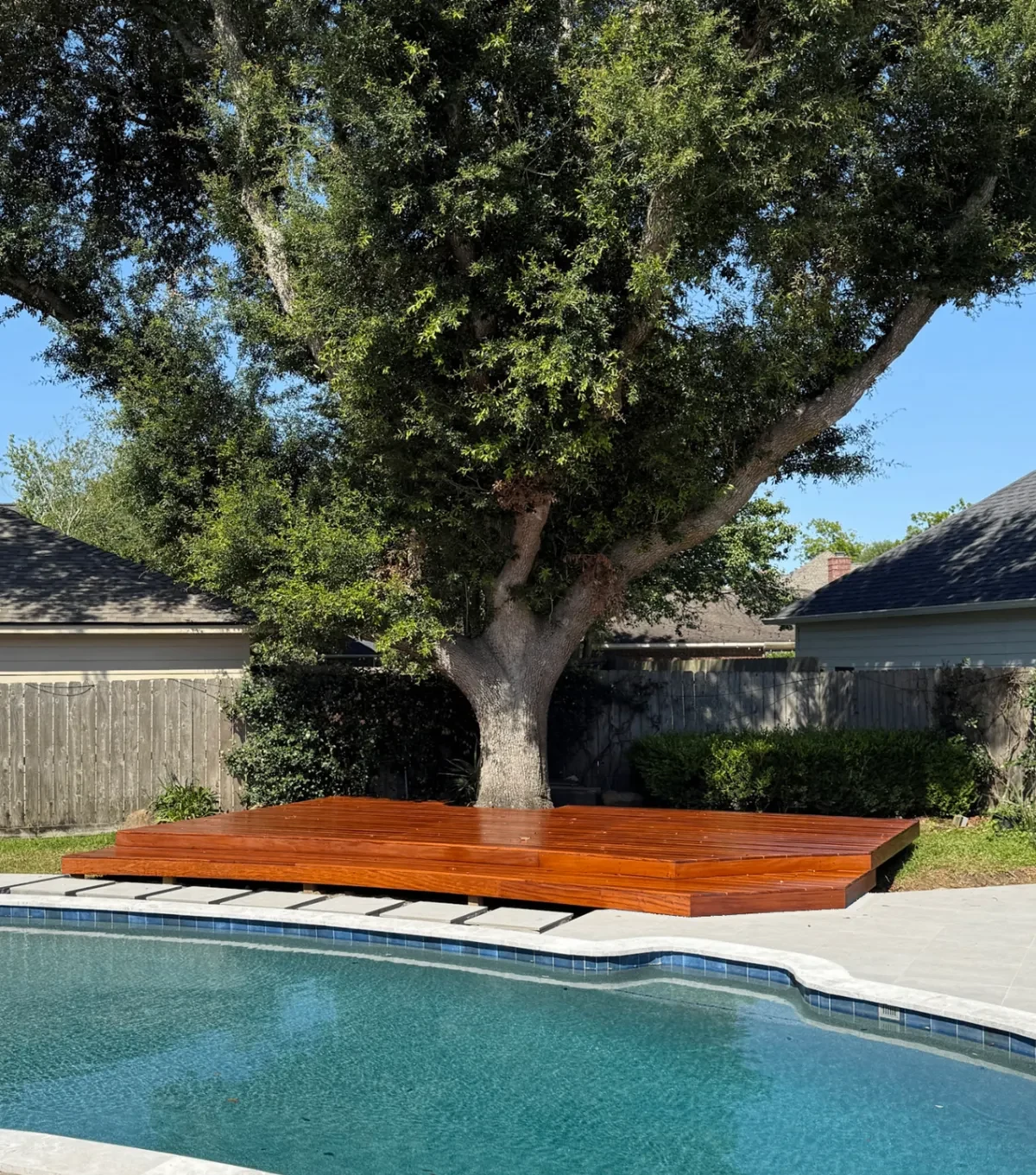 A low hardwood deck built around a mature live oak beside a swimming pool at a Houston-area Right Angle project.