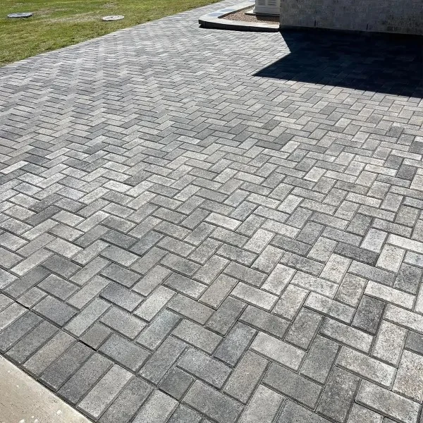 Tumbled grey concrete pavers in a herringbone field beside a lawn at a commercial Right Angle project in the Houston Heights.