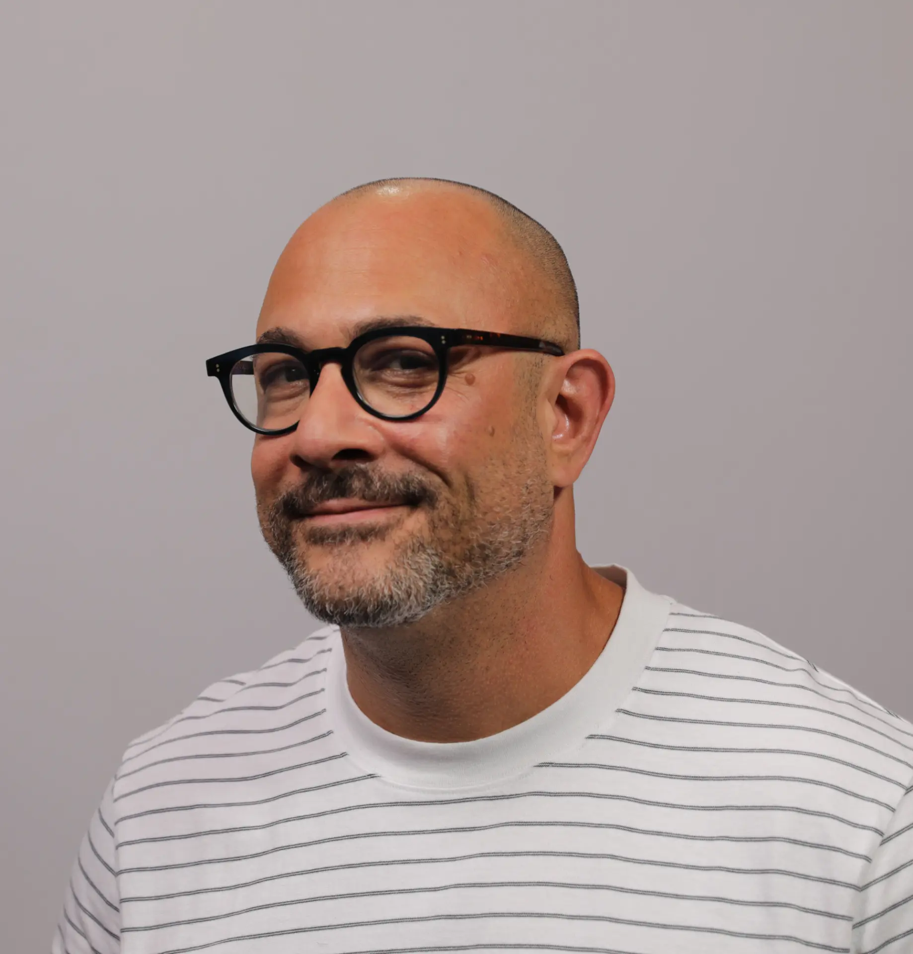 Portrait of Omar Afra wearing black glasses and a white striped shirt